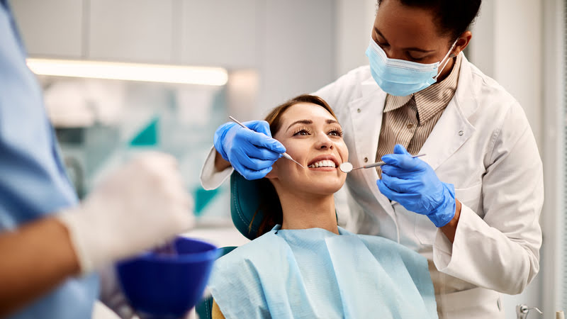 Kobieta w gabinecie stomatologicznym uśmiecha się po wykonanym zabiegu bondingu zębów.